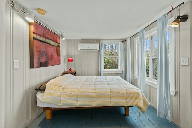 bedroom with a wall mounted air conditioner, wood-type flooring, and wood walls