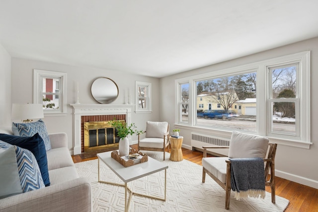 living room with radiator, a fireplace, and light wood-type flooring