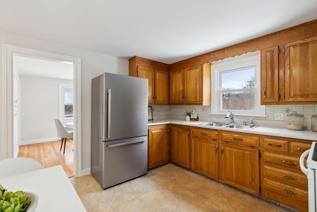 kitchen with tasteful backsplash, sink, range, and stainless steel refrigerator