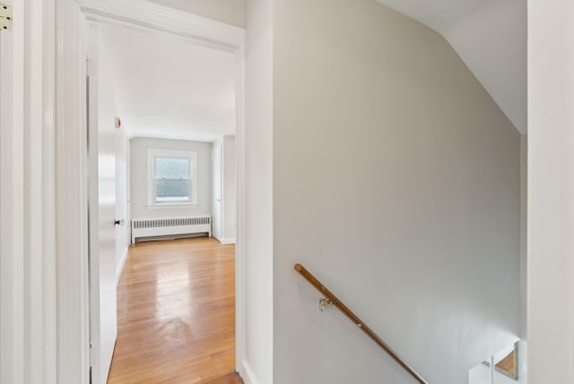 corridor with lofted ceiling, radiator, and light hardwood / wood-style flooring