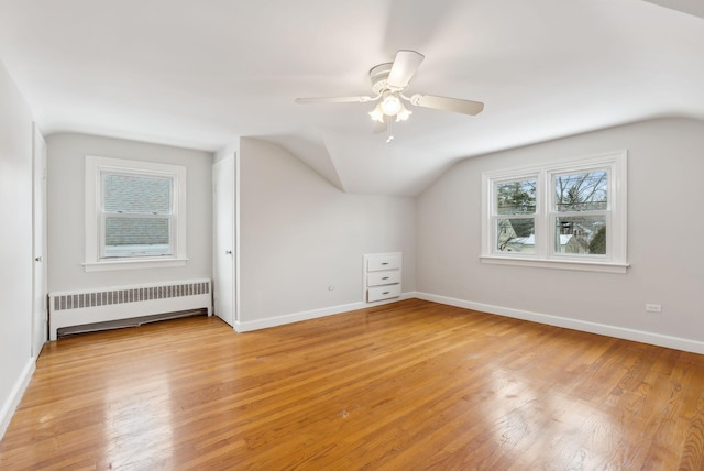 additional living space featuring ceiling fan, lofted ceiling, radiator, and light wood-type flooring