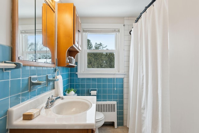 bathroom with tile walls, radiator, plenty of natural light, and toilet