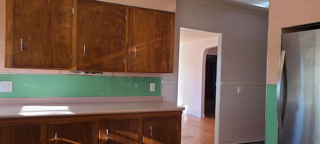 kitchen featuring stainless steel refrigerator, crown molding, and light hardwood / wood-style floors