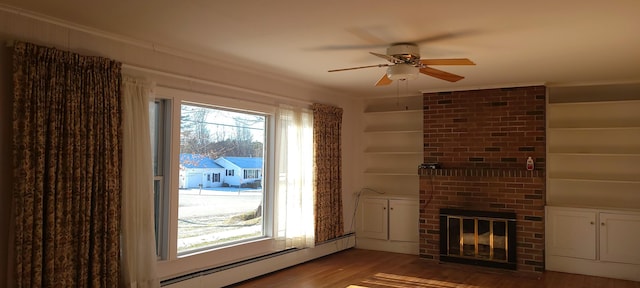 unfurnished living room featuring built in shelves, ceiling fan, a baseboard radiator, a brick fireplace, and wood-type flooring