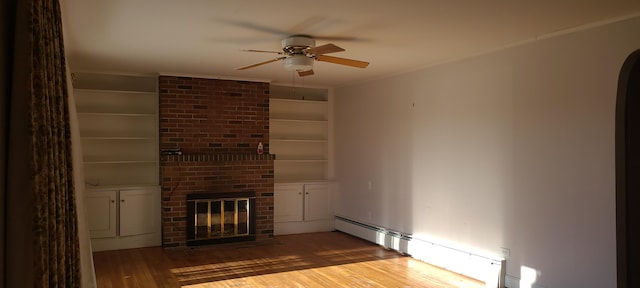 unfurnished living room with baseboard heating, ceiling fan, built in features, a fireplace, and dark hardwood / wood-style floors