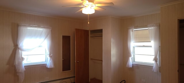 interior space with ceiling fan, crown molding, and a baseboard heating unit