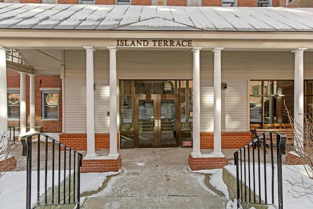 snow covered property entrance with a porch and french doors