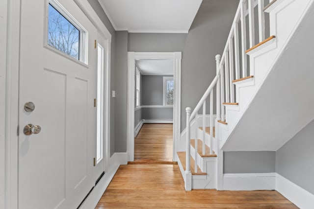 foyer entrance featuring a healthy amount of sunlight, ornamental molding, and light hardwood / wood-style flooring