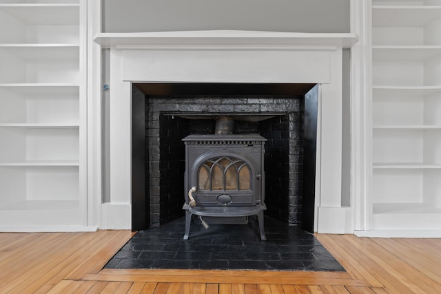 room details with a wood stove, built in features, and hardwood / wood-style flooring