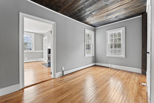 unfurnished room featuring hardwood / wood-style flooring, a wood stove, wood ceiling, and a baseboard heating unit