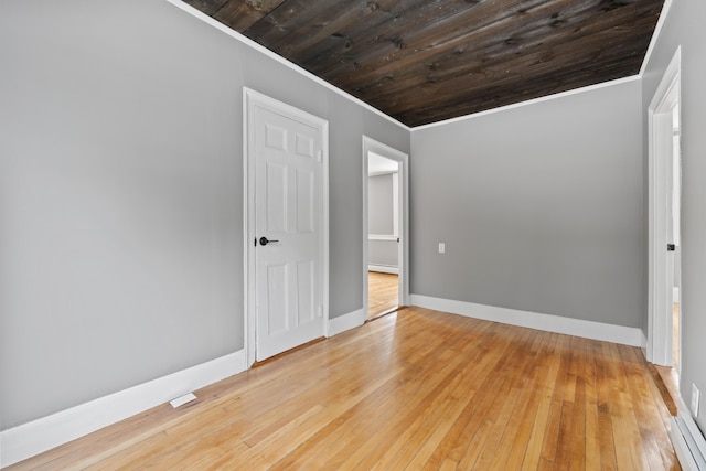 unfurnished bedroom featuring baseboard heating, ornamental molding, wooden ceiling, and hardwood / wood-style flooring