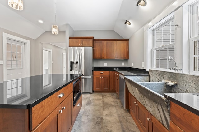 kitchen with appliances with stainless steel finishes, tasteful backsplash, pendant lighting, dark stone countertops, and lofted ceiling