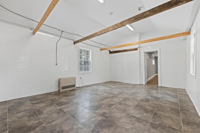 empty room with vaulted ceiling with beams, brick wall, and heating unit