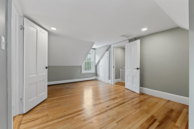 bonus room featuring baseboard heating, light hardwood / wood-style floors, and lofted ceiling