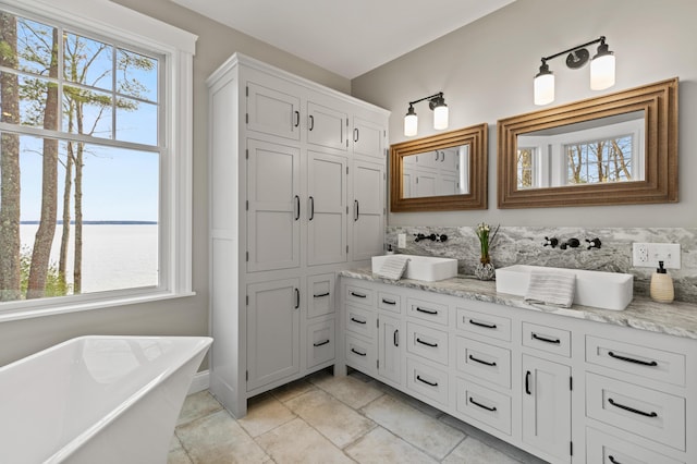 18 Sheehans Island Rd, Raymond, ME 04071 - full bathroom featuring double vanity, a freestanding bath, a water view, and tile patterned floors