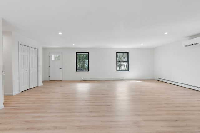 17 Ward Rd, Sebago, ME 04029 - unfurnished living room with baseboard heating, light wood-type flooring, a baseboard heating unit, a wall mounted air conditioner, and recessed lighting