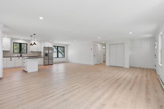17 Ward Rd, Sebago, ME 04029 - unfurnished living room featuring a sink, light wood-style flooring, recessed lighting, and a baseboard heating unit