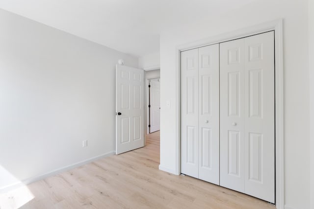 17 Ward Rd, Sebago, ME 04029 - unfurnished bedroom featuring a closet, baseboards, and light wood finished floors