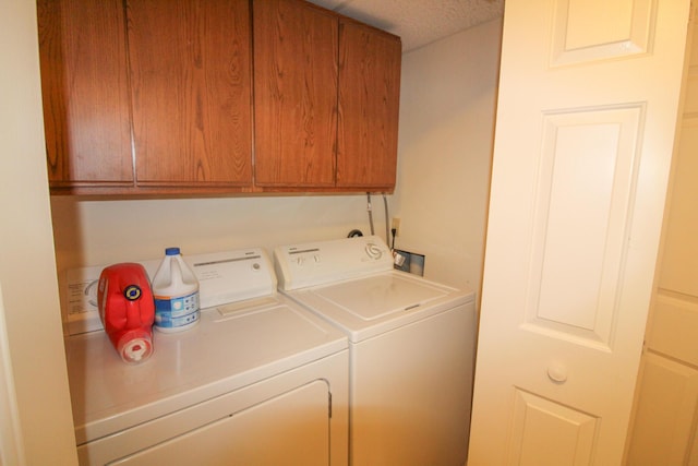 laundry room with cabinets, a textured ceiling, and washing machine and clothes dryer