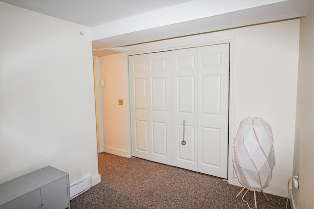 unfurnished bedroom featuring a closet, dark carpet, and a baseboard heating unit