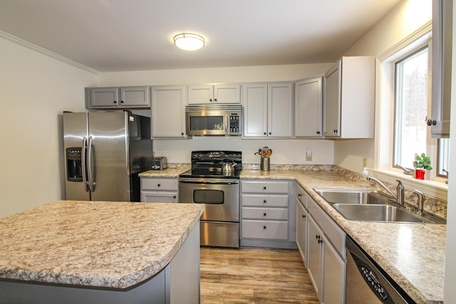 kitchen with gray cabinetry, sink, light wood-type flooring, appliances with stainless steel finishes, and ornamental molding