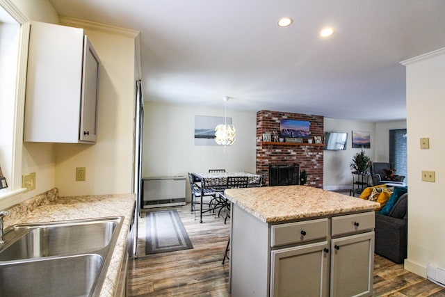 kitchen with sink, hanging light fixtures, dark hardwood / wood-style flooring, a fireplace, and a kitchen island