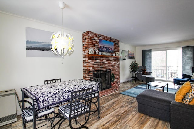 dining room with crown molding, a fireplace, wood-type flooring, and an inviting chandelier