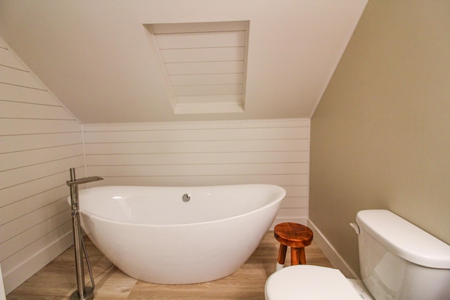 bathroom featuring wood-type flooring, toilet, a tub, and wood walls