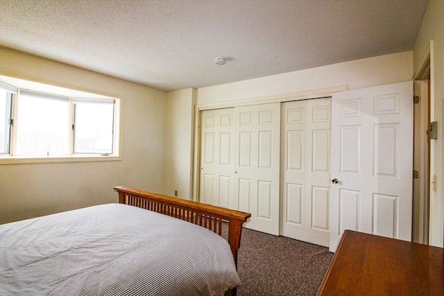 bedroom featuring a closet, a textured ceiling, and dark colored carpet