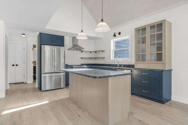 kitchen with a kitchen island, sink, stainless steel fridge, blue cabinetry, and wall chimney exhaust hood