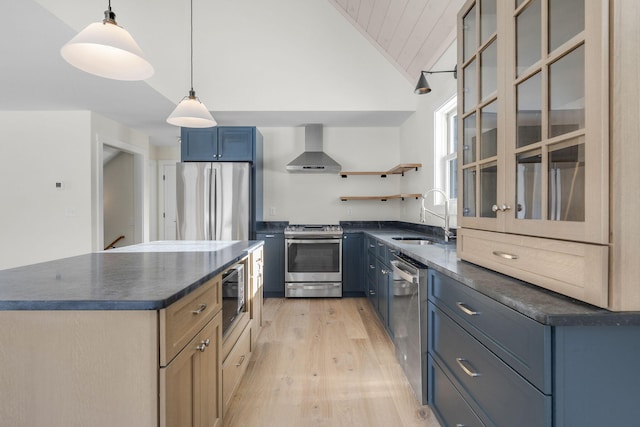 kitchen featuring blue cabinetry, wall chimney exhaust hood, sink, vaulted ceiling, and appliances with stainless steel finishes