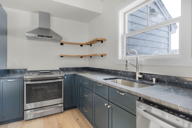 kitchen featuring stainless steel appliances, sink, light wood-type flooring, and wall chimney exhaust hood