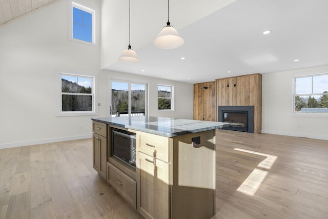 kitchen featuring a kitchen island, dark stone countertops, light hardwood / wood-style floors, and decorative light fixtures