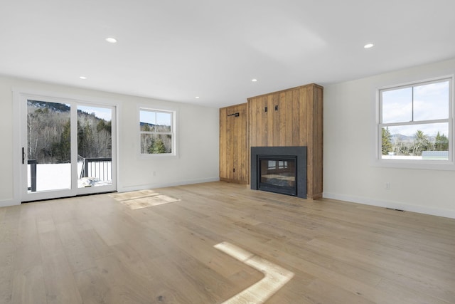 unfurnished living room with a large fireplace and light hardwood / wood-style floors