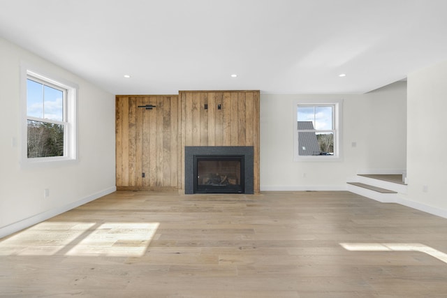 unfurnished living room with plenty of natural light, a large fireplace, and light wood-type flooring