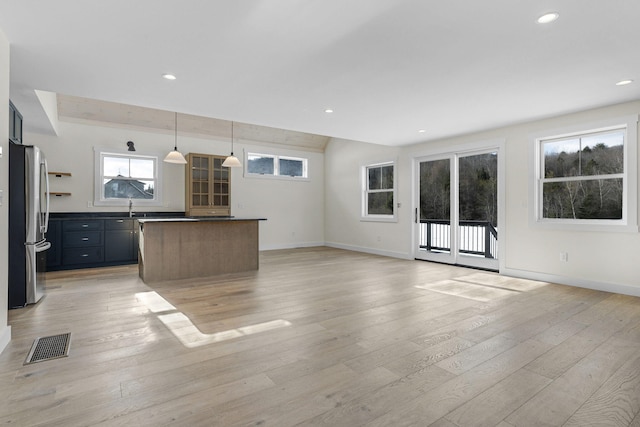 unfurnished living room featuring sink and light hardwood / wood-style floors