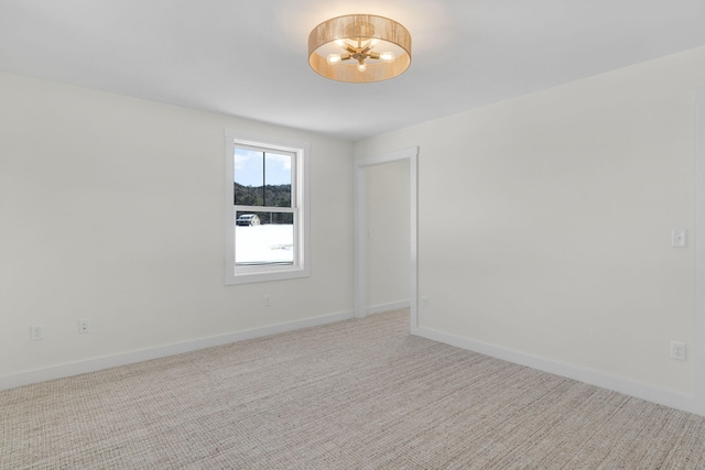 spare room featuring a chandelier and light carpet