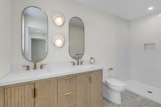 bathroom with vanity, tiled shower, and toilet