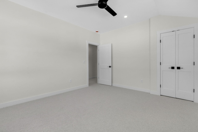 unfurnished bedroom featuring light carpet, lofted ceiling, a closet, and ceiling fan