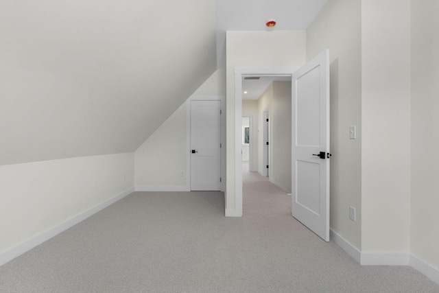 additional living space featuring light carpet and vaulted ceiling