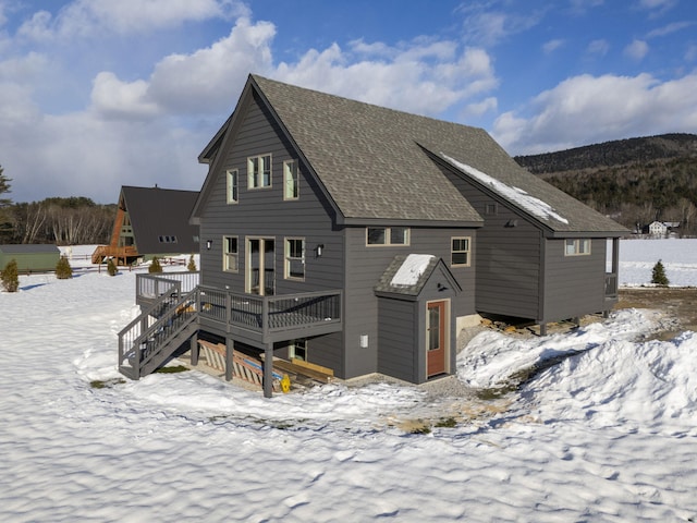 snow covered rear of property featuring a deck