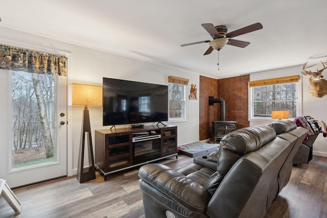 living room with hardwood / wood-style flooring, ceiling fan, and a wood stove