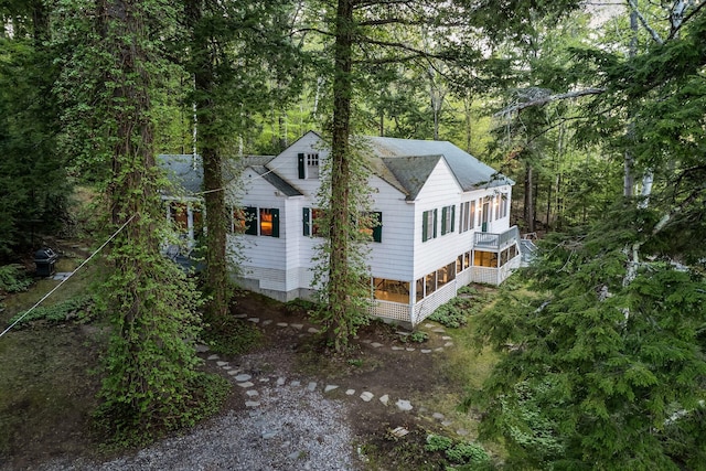 137 Birch Ln, Belgrade, ME 04917 - view of front facade featuring a sunroom, stairway, a shingled roof, and a view of trees