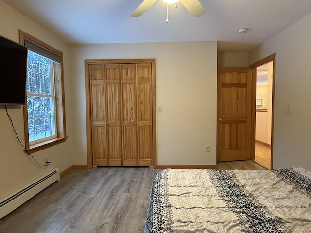 unfurnished bedroom featuring ceiling fan, a closet, light wood-type flooring, and a baseboard heating unit