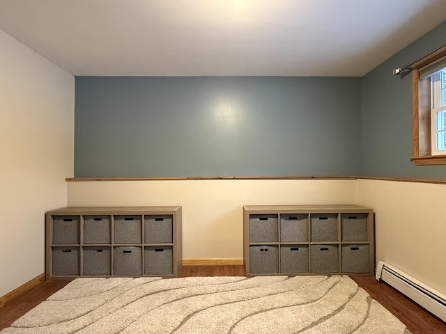 bedroom with dark wood-type flooring and a baseboard heating unit