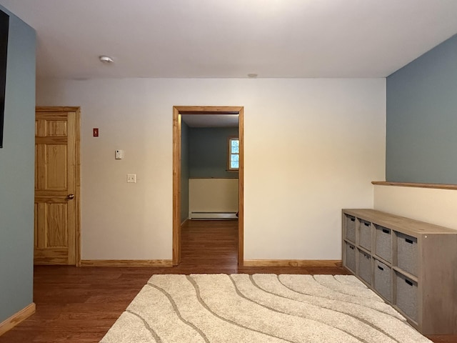 bedroom with dark hardwood / wood-style flooring and a baseboard heating unit