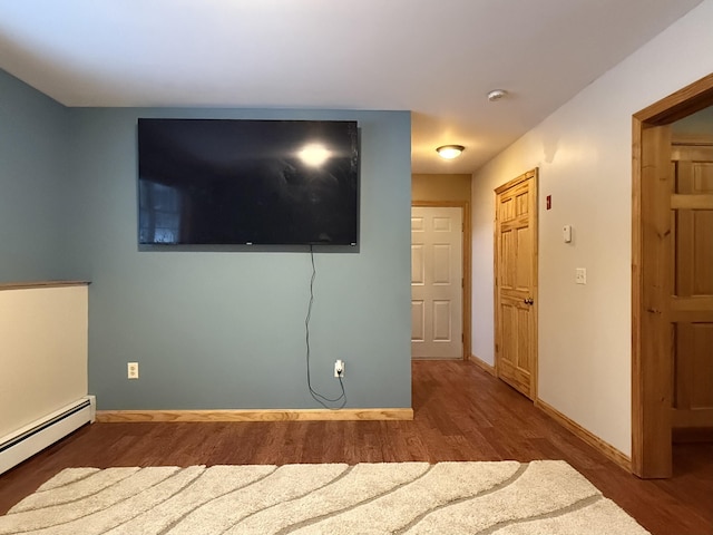 unfurnished bedroom featuring baseboard heating and dark wood-type flooring