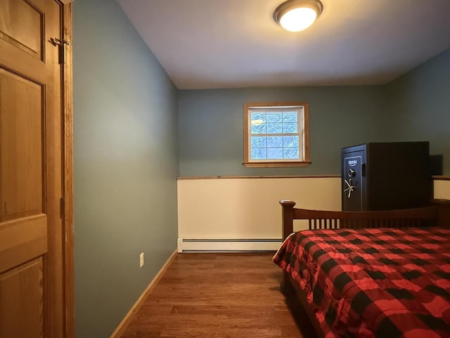 bedroom with wood-type flooring and a baseboard heating unit