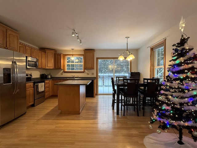 kitchen featuring stainless steel appliances, pendant lighting, an inviting chandelier, light hardwood / wood-style floors, and a kitchen island