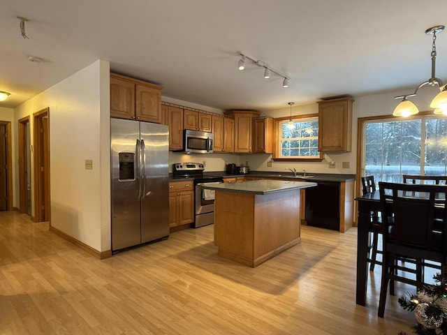 kitchen featuring decorative light fixtures, a center island, stainless steel appliances, and light hardwood / wood-style floors